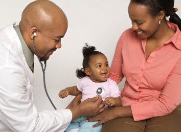 doctor examining young child while mother present