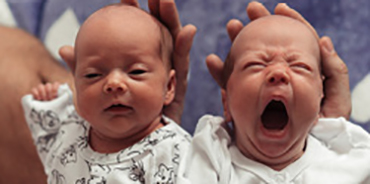 two newborn babies, one yawning