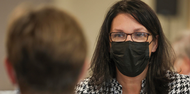 Minister of Health Michelle Thompson speaking to a member of the public while wearing a mask