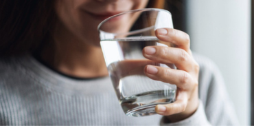 woman drinking water from a clear glass