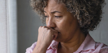 woman with fist over her mouth looking anxious