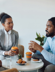 a black man and woman in conversation while sitting at a small table
