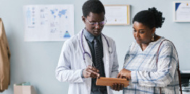 Black physician in white coat with Black woman patient