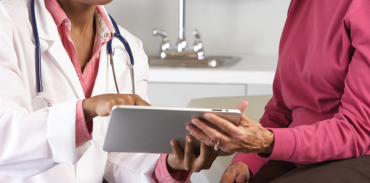 Female physician and patient chatting while looking at a tablet