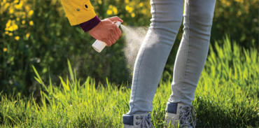 individual putting on tick repellent spray