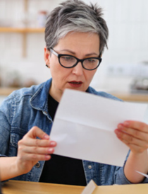 woman wearing a jean shirt with black t-shirt underneath and looking at a piece of paper looking concerned