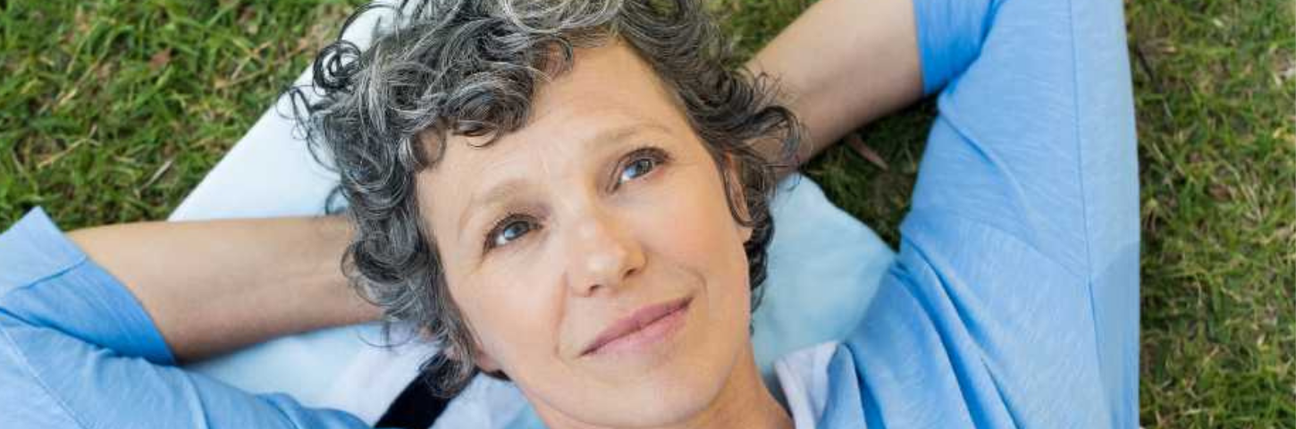 woman wearing a blue long sleeved shirt and laying on the grass