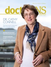 Dr. Cathy Connell wearing a white sweater and scarf with light brown wool blazer on the cover of the March issue of doctorsNS magazine