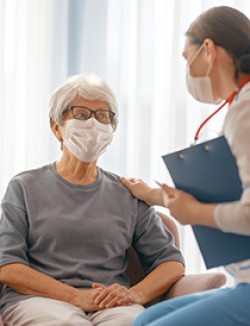 Female physician speaking with female patient, both wearing masks