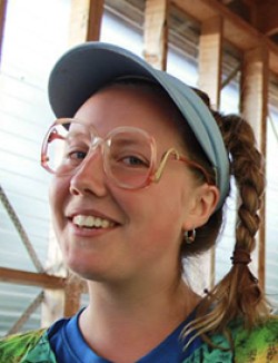 young girl wearing colourful shirt and glasses, visor and long hair braid