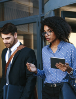 a man and woman dressed in business attire walking out of an office building