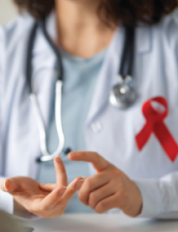 female physician wearing white coat and stethoscope with a red ribbon pinned to her coat