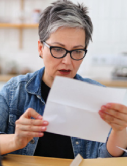 woman wearing a jean shirt with black t-shirt underneath and looking at a piece of paper looking concerned