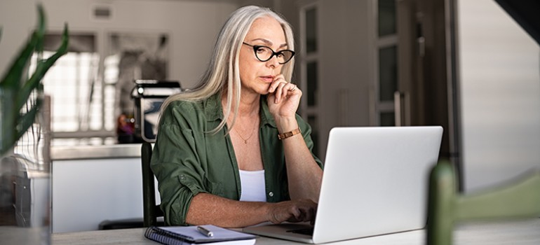 woman sitting in her kitchen and working on her laptop computer