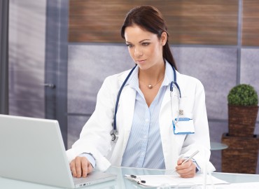 Female physician sitting at a desk infront of a comuter