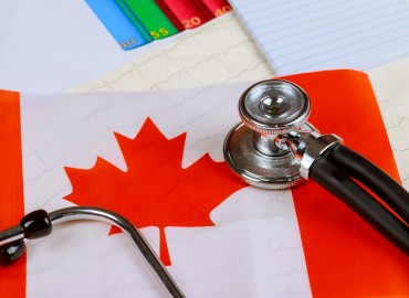 a stethascope sits onto of a Canadian flag on a desk