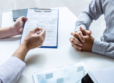 medical professional with form on clipboard, sitting across from someone