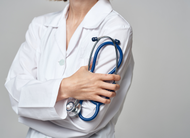 a medical professional stands with arms crossed holding a blue stethascope on their left