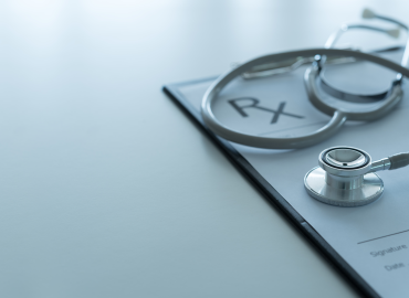 prescription pad on a white desk with a stethascope ontop of the pad