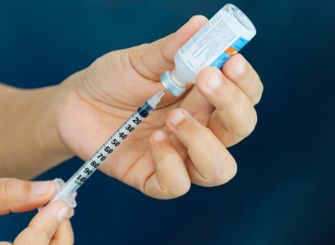 a needle is inserted into an insulin bottle