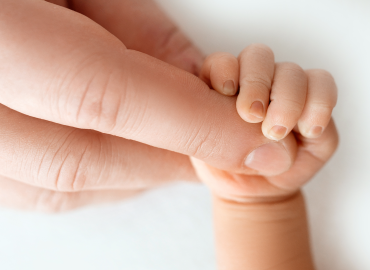 newborn baby grasps adult finger