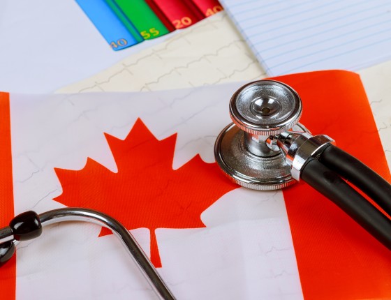 a stethascope sits onto of a Canadian flag on a desk