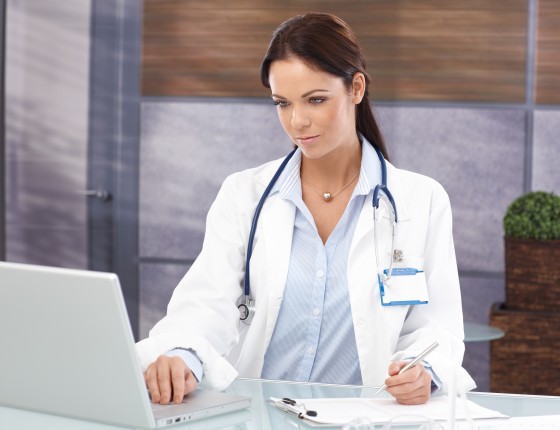female physician sits infront of a laptop at desk