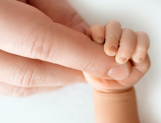 newborn baby grasps adult finger