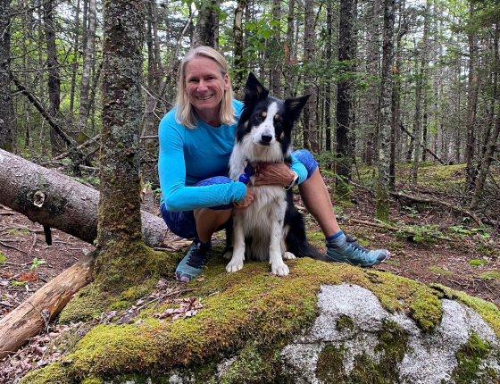 Kerry Copeland sits on log with her dog Beau